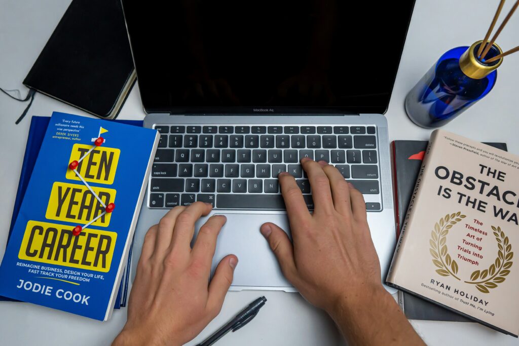 Scholar writing a dissertation on a laptop with reference books on the desk