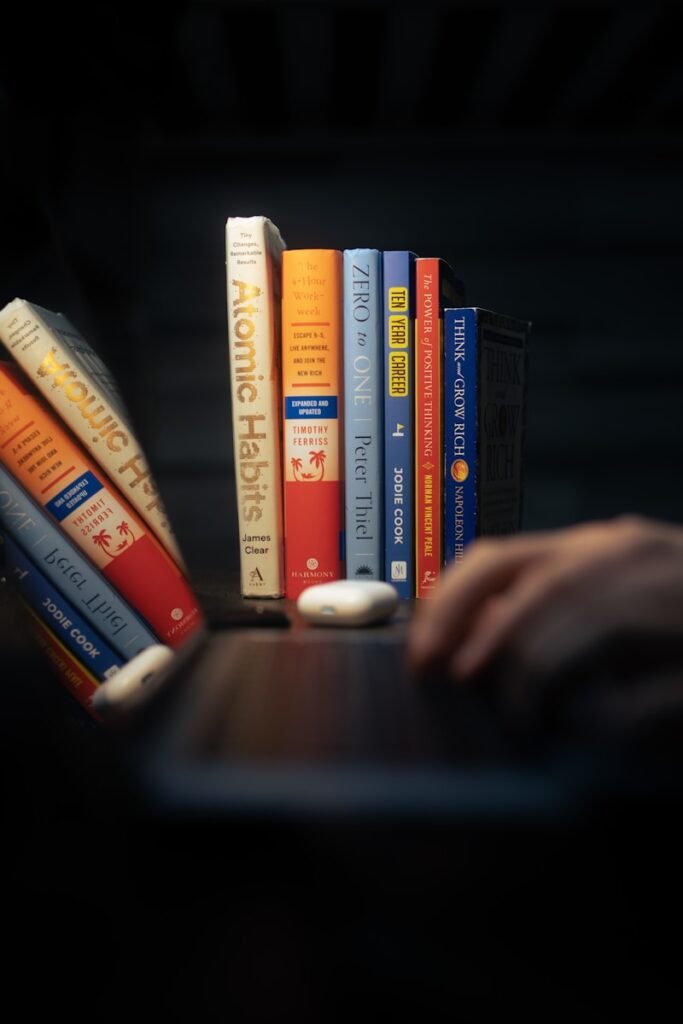 a person is typing on a laptop with a bunch of books